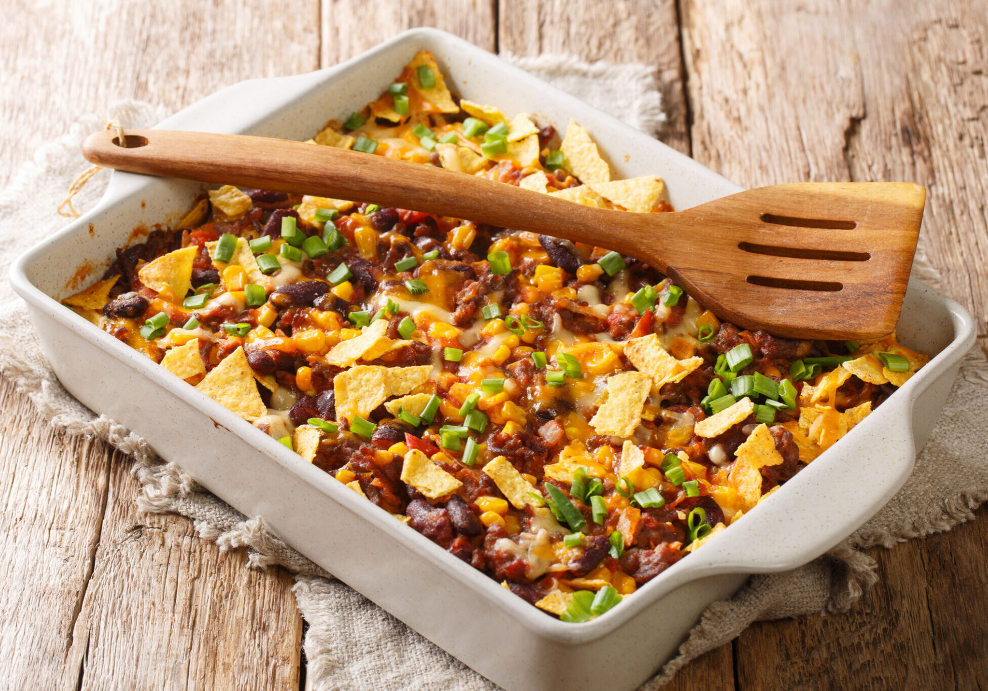 Crispy homemade frito pie with beef, cheese, corn, beans and chips close-up in a baking dish. horizontal