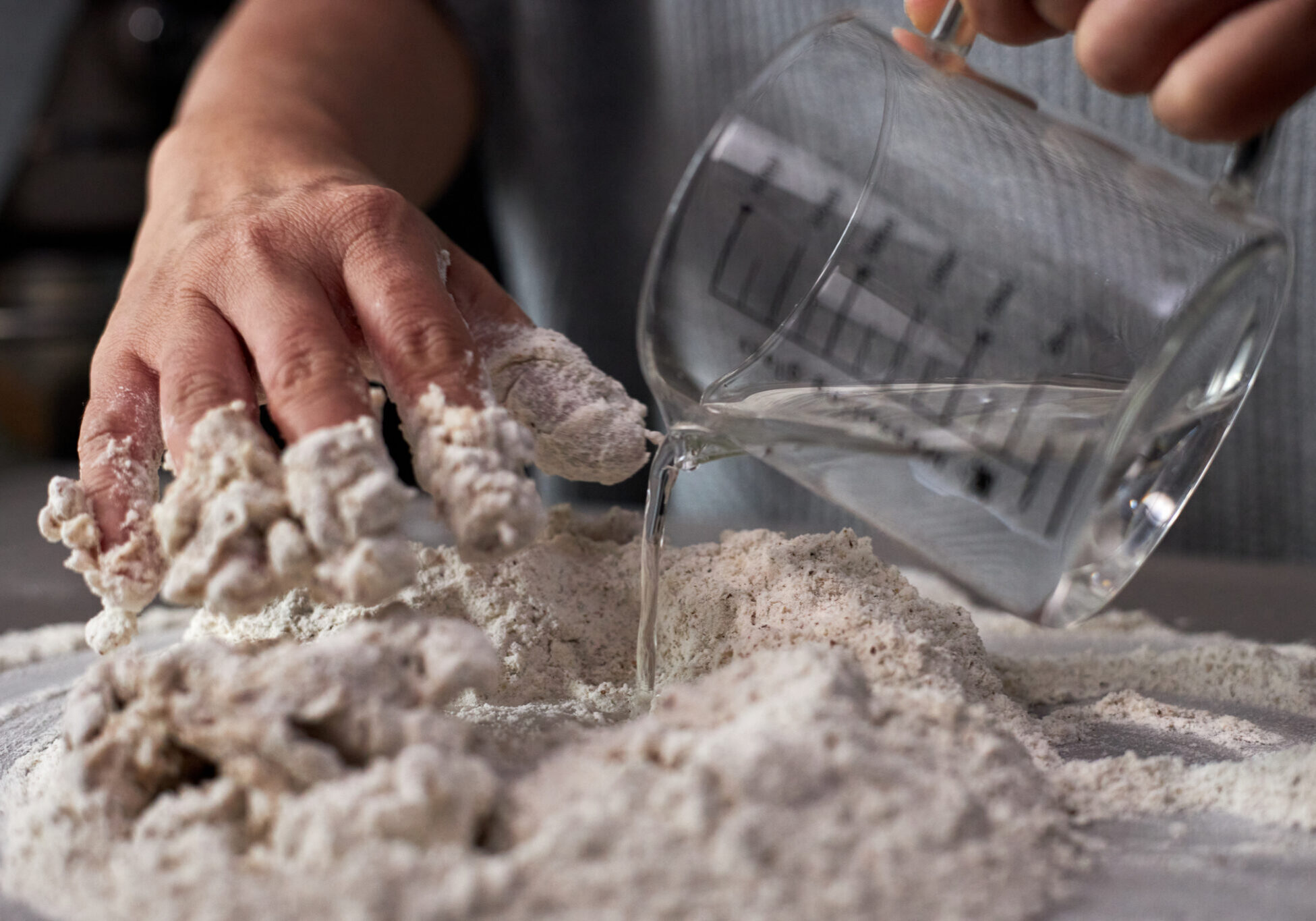 Pouring water into wholewheat flour, for kneading bread dough