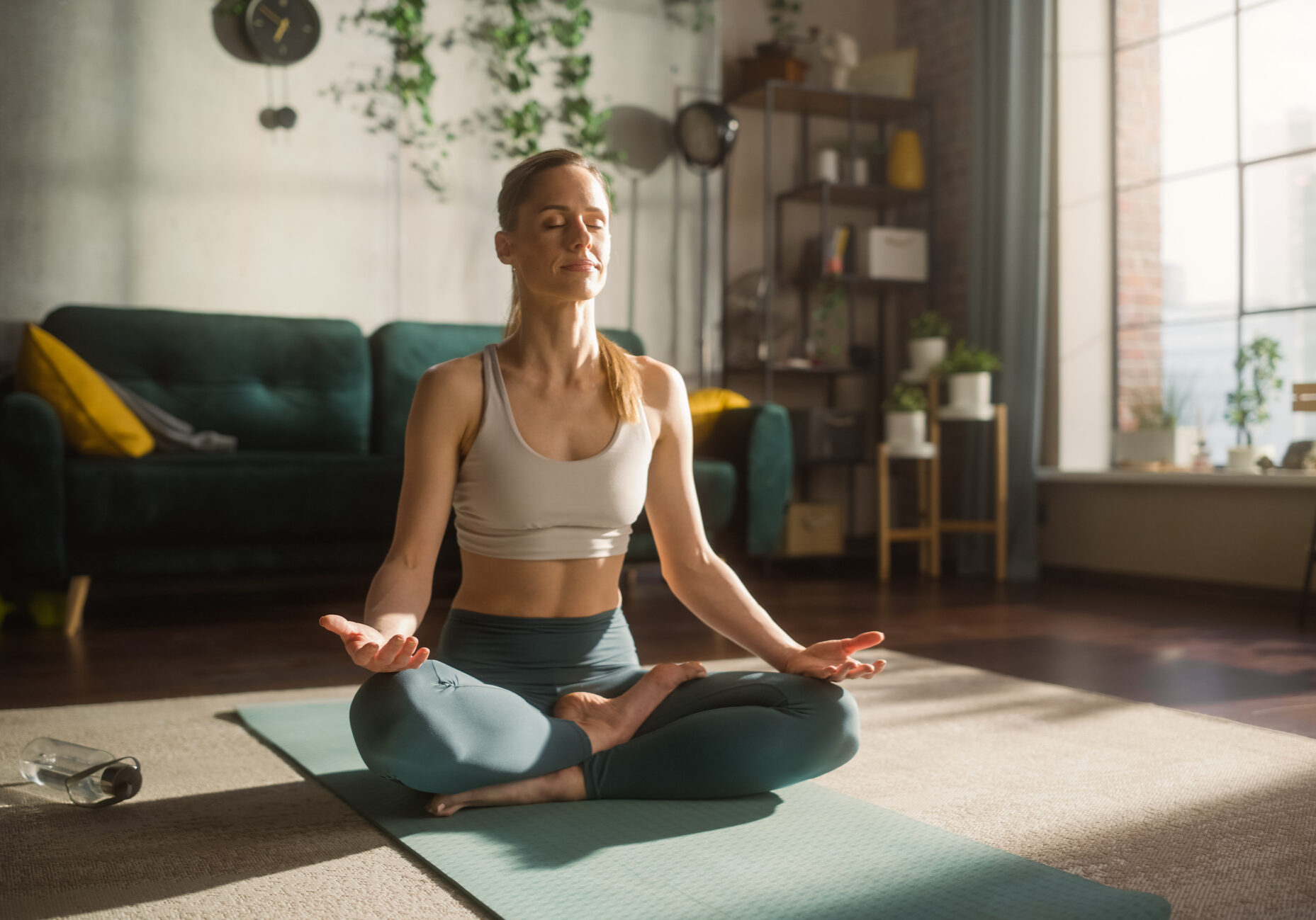 Young Athletic Woman Exercising, Practising Meditation in the Morning in Her Bright Sunny Home Living Room. Healthy Lifestyle, Fitness, Wellbeing and Mindfulness Concept.