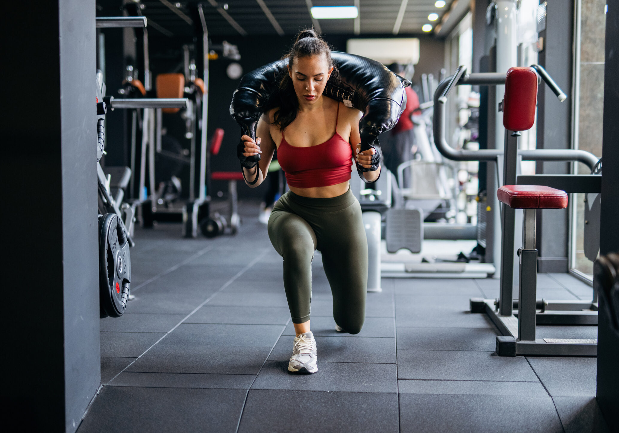 Athletic woman performing lunges with heavy weight.